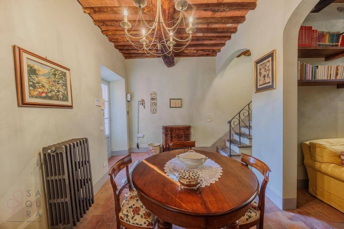Eleganter Essbereich mit ovalem Holztisch, Kronleuchter und Terrakottaboden, angrenzend an eine Treppe.