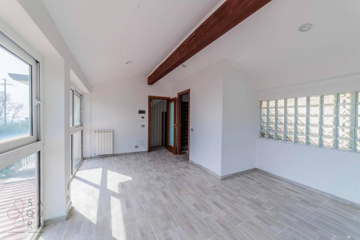 Heller Wohnraum mit Fliesenboden, Holzbalken und Glasbausteinwand für natürliches Licht.