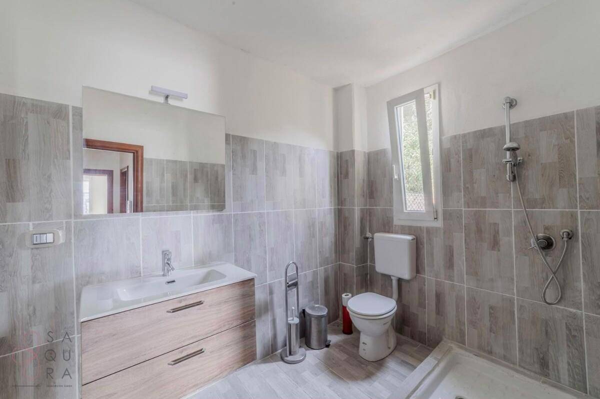 Modernes Badezimmer mit Waschtisch, WC, Dusche und Fenster für Tageslicht.