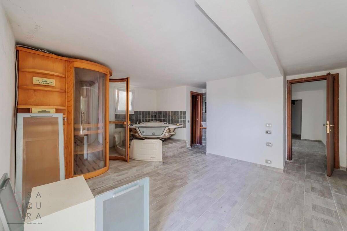 Wellnessbereich mit Sauna, Whirlpool und Fliesenboden, ideal zur Entspannung.