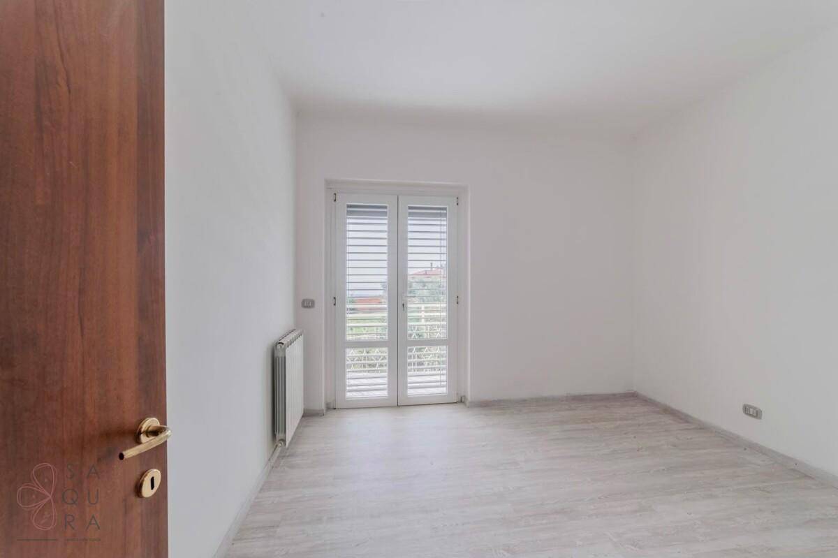 Schlafzimmer mit Balkontür, Fliesenboden und Heizkörper, ideal für individuelle Einrichtung.