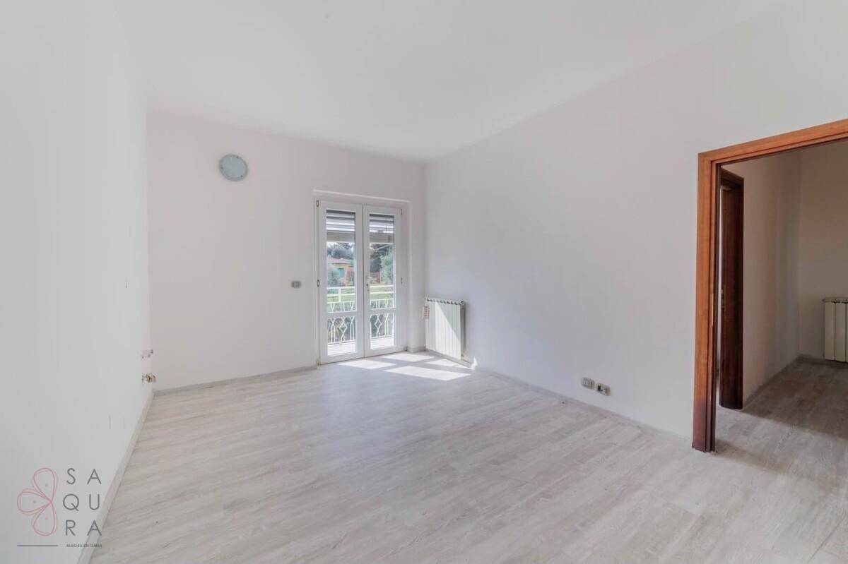 Helles Schlafzimmer mit Balkonzugang, Fliesenboden und viel Tageslicht.