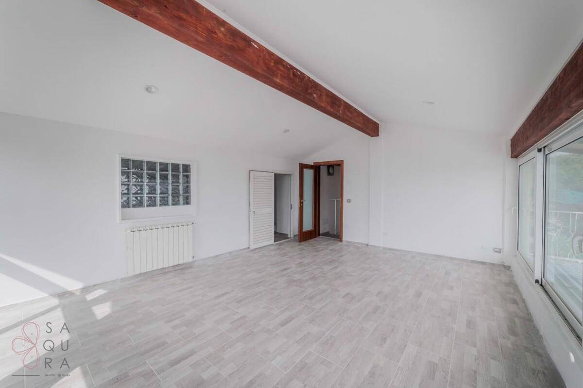 Geräumiger Wohnbereich mit Holzbalken, Glasbausteinwand und Fliesenboden.