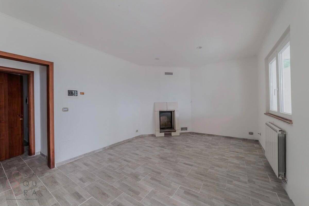 Wohnzimmer mit Kamin, hellen Wänden und Fliesenboden, bereit zur individuellen Gestaltung.