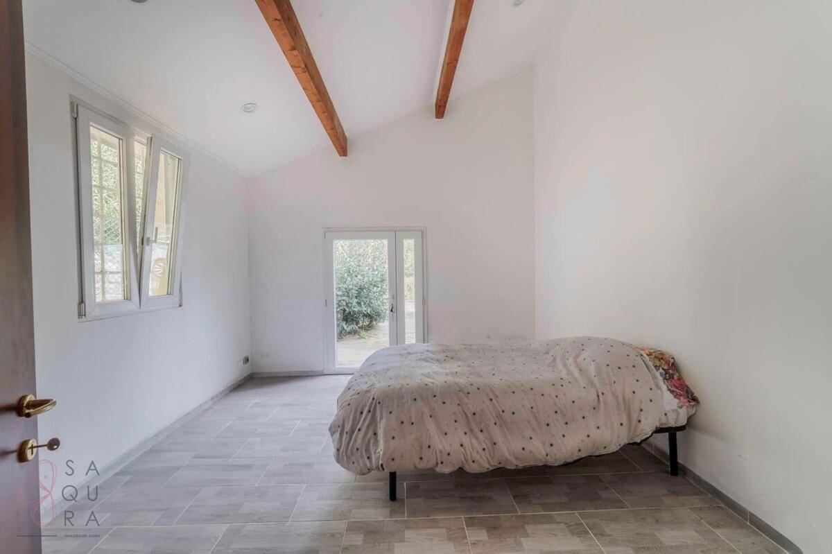 Schlafzimmer mit hohen Decken, sichtbaren Holzbalken und Zugang zum Garten.