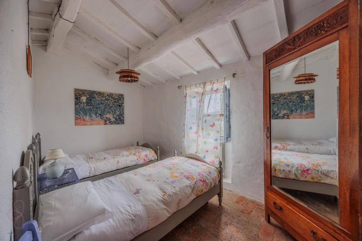 Kinderzimmer mit zwei Einzelbetten, Terrakottafliesen und einem großen Spiegel.