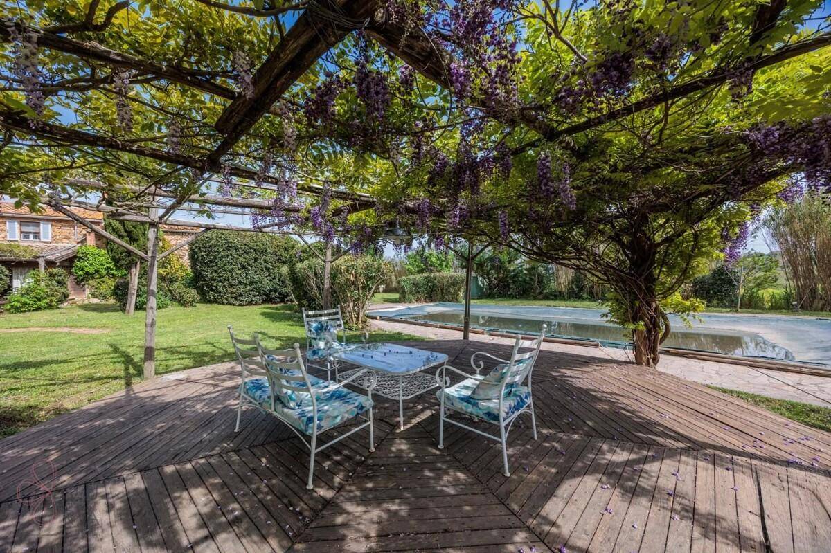 Gemütlicher Sitzbereich im Freien unter einer blühenden Pergola, ideal zum Entspannen am Pool.