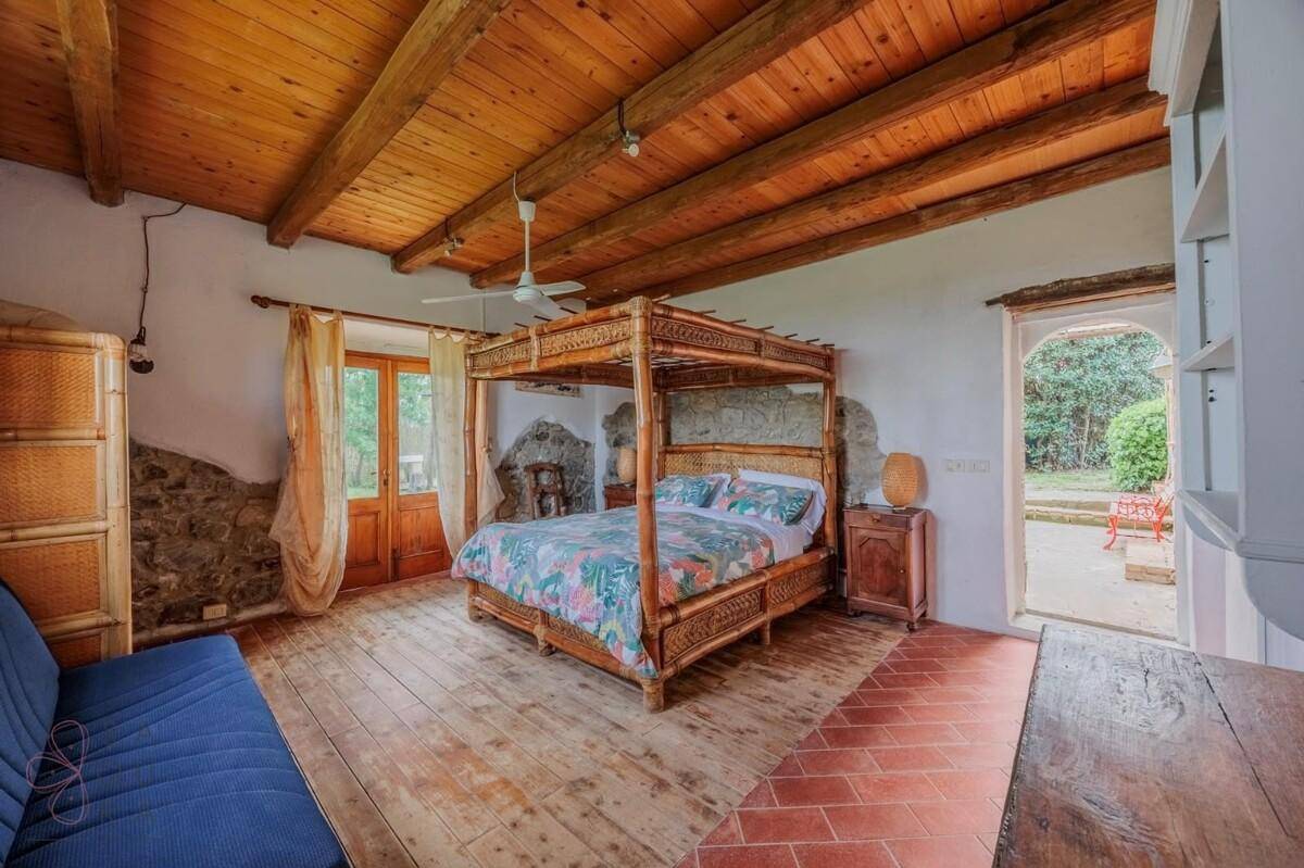 Rustikales Schlafzimmer mit Himmelbett, Holzbalkendecke und direktem Zugang zum Garten.