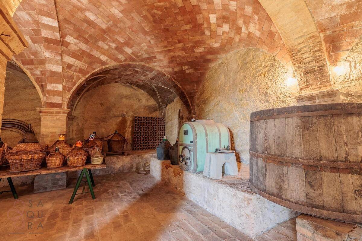 Historischer Weinkeller mit Ziegelgewölbedecke, großen Holzfässern und traditionellen Weinutensilien.