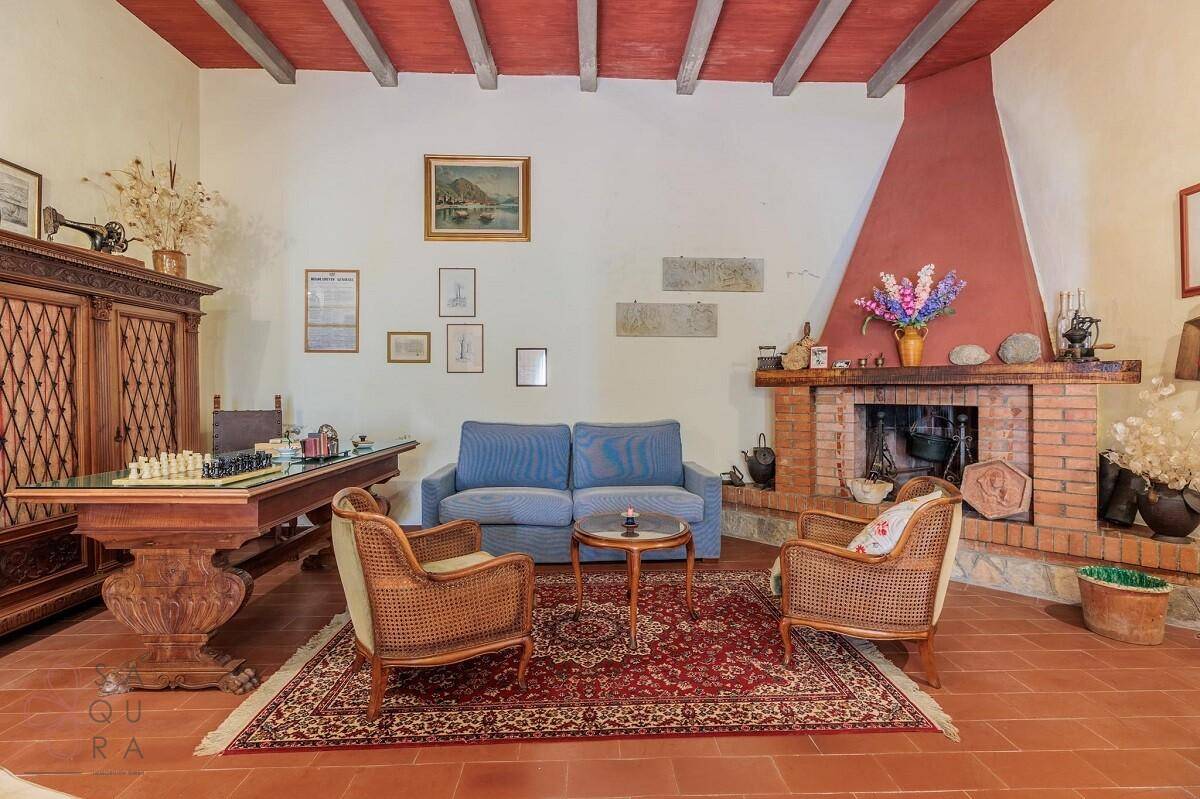 Gemütliches Wohnzimmer mit traditionellem Kamin, Terrakottaboden und rustikalen Holzmöbeln.