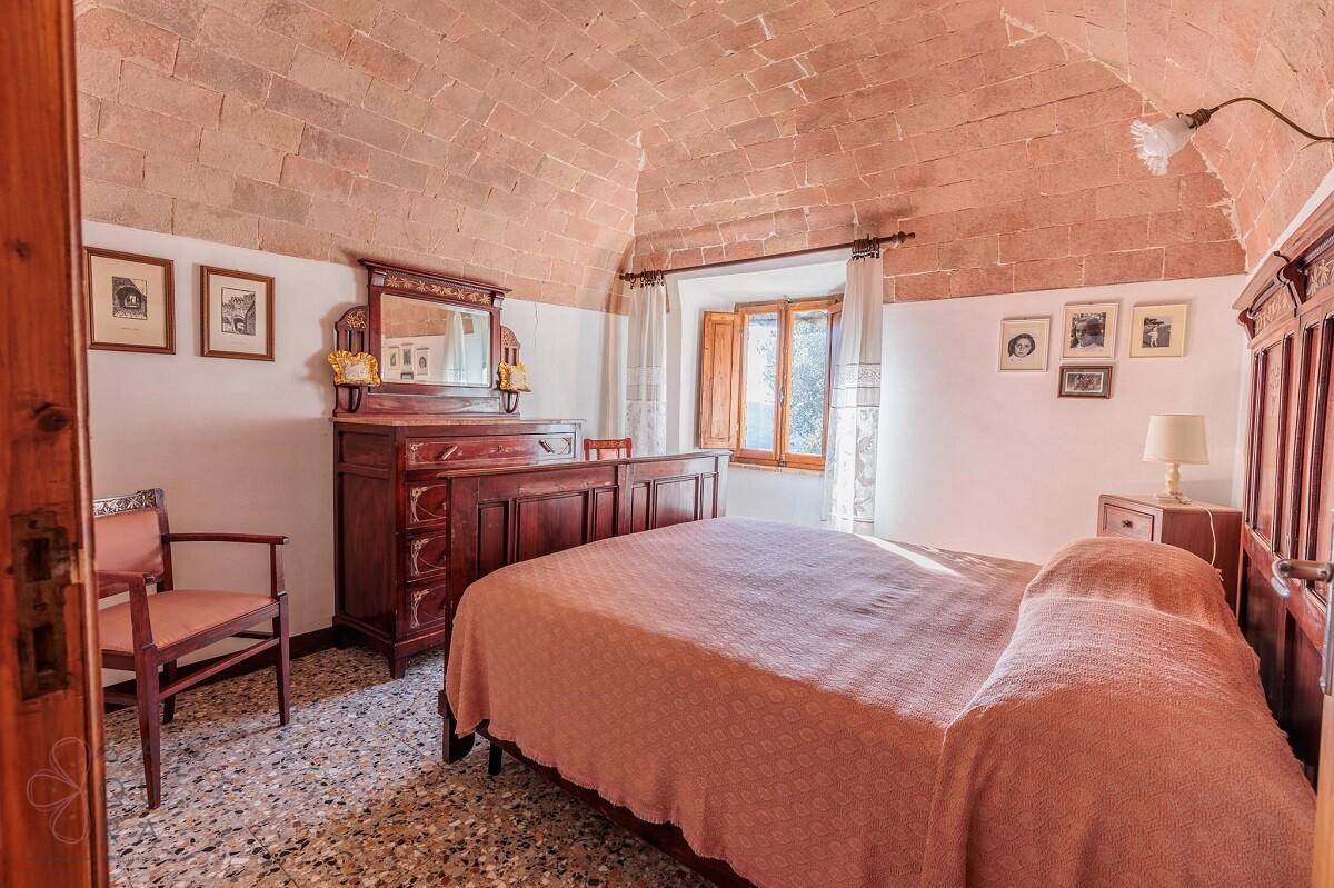 Geräumiges Schlafzimmer mit Terrazzoboden, Ziegelgewölbedecke und traditionellen Holzmöbeln.