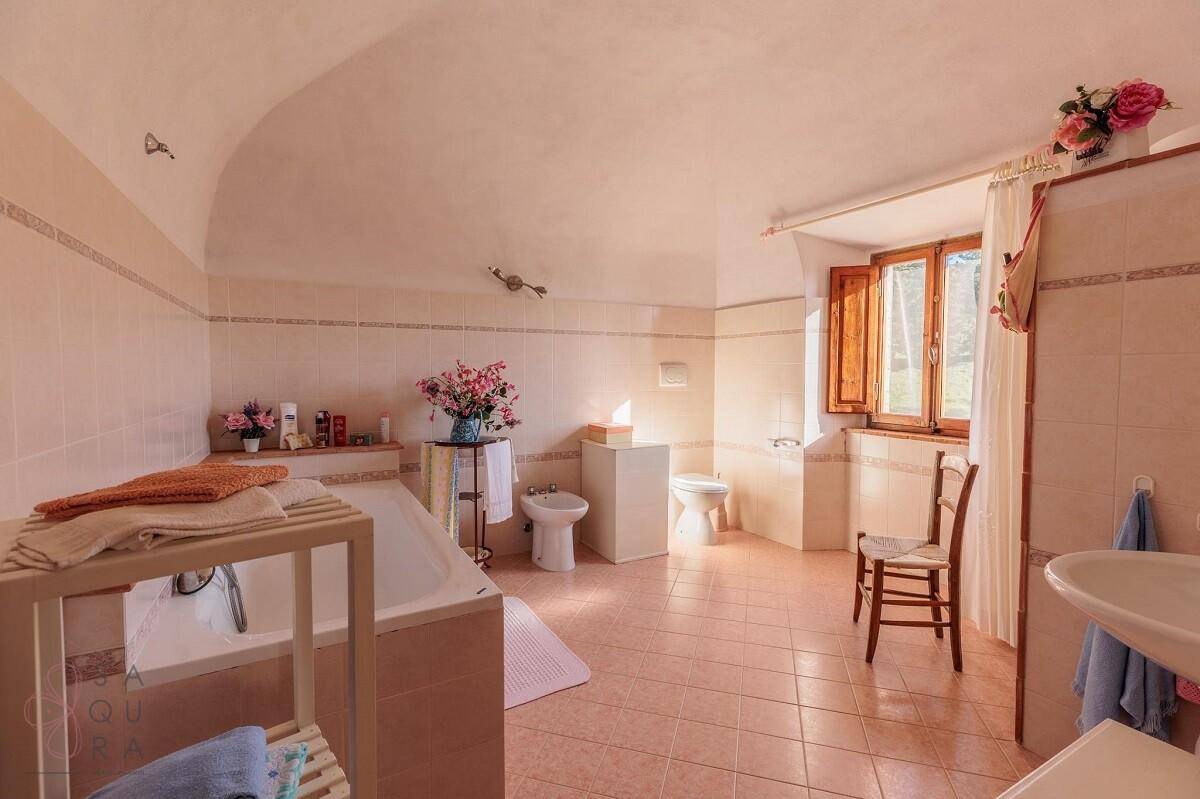 Geräumiges Badezimmer mit Badewanne, Bidet, WC, rosa Fliesen und einem Fenster.
