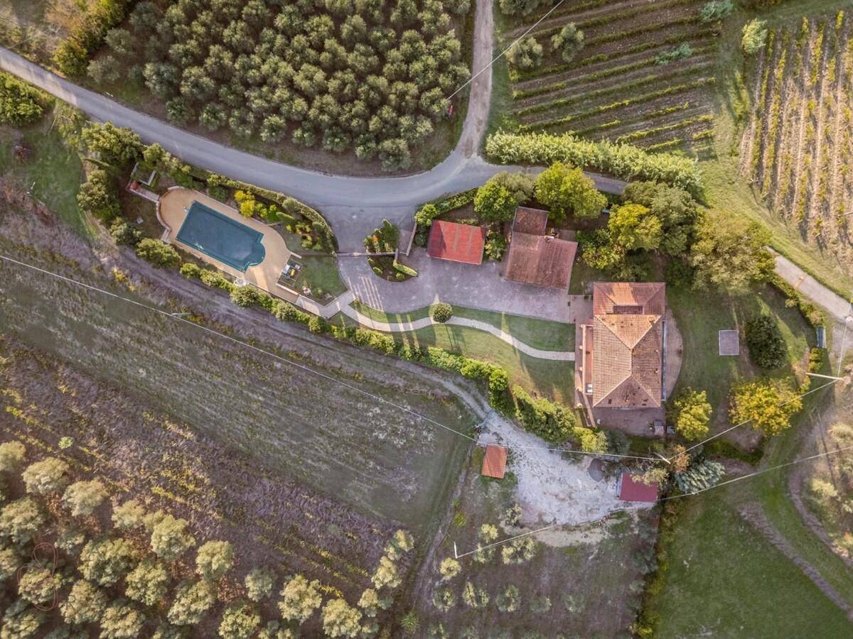Draufsicht des Anwesens mit Hauptgebäude, Nebengebäuden, Pool und umliegenden landwirtschaftlichen Flächen.