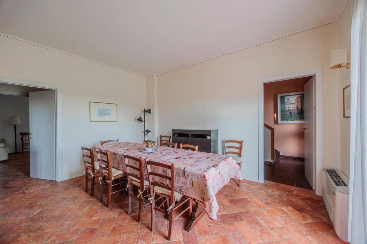Geräumiger Essbereich mit großem Holztisch, Terracotta-Fliesenboden und Zugang zu weiteren Räumen.
