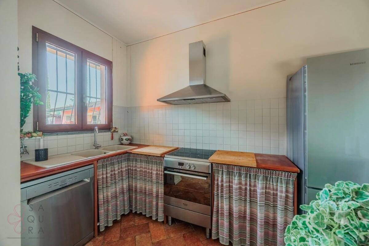 Funktionale Küche mit Terracotta-Boden, weißem Fliesenspiegel und modernen Geräten.