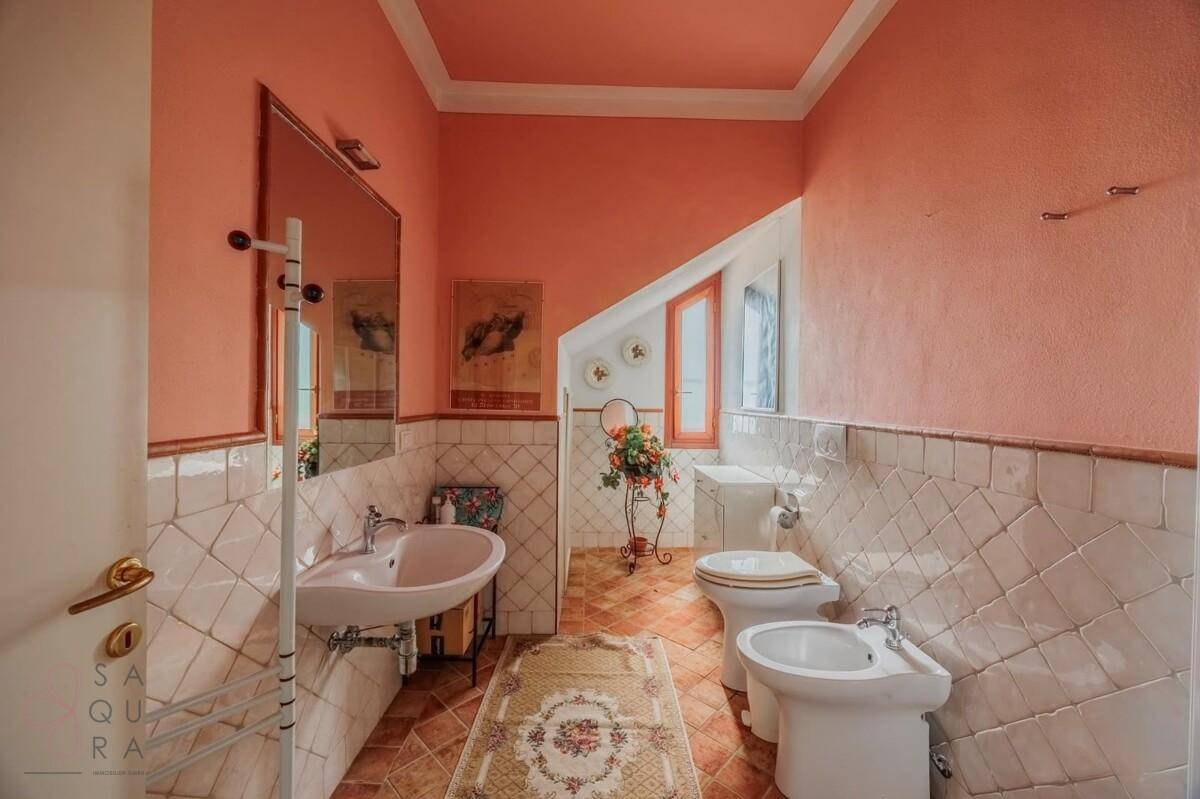 Badezimmer mit rosa Wänden, weißen und rosa Fliesen, Waschbecken, WC und Bidet.