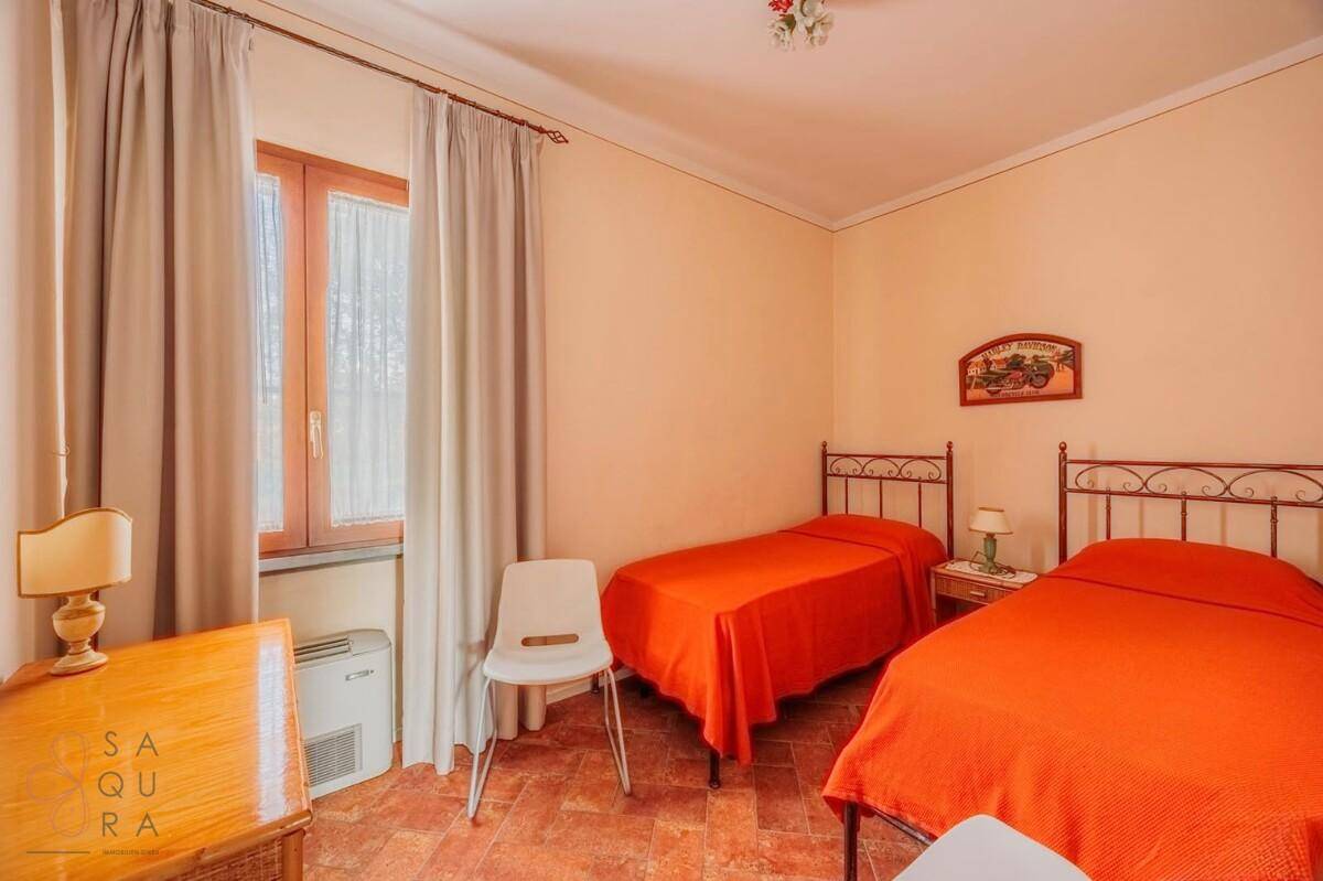 Schlafzimmer mit zwei Einzelbetten, Terracotta-Fliesenboden und einem Fenster.