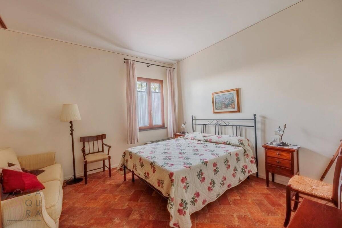 Helles Schlafzimmer mit Doppelbett, Sofa und traditionellem Terracotta-Fliesenboden.