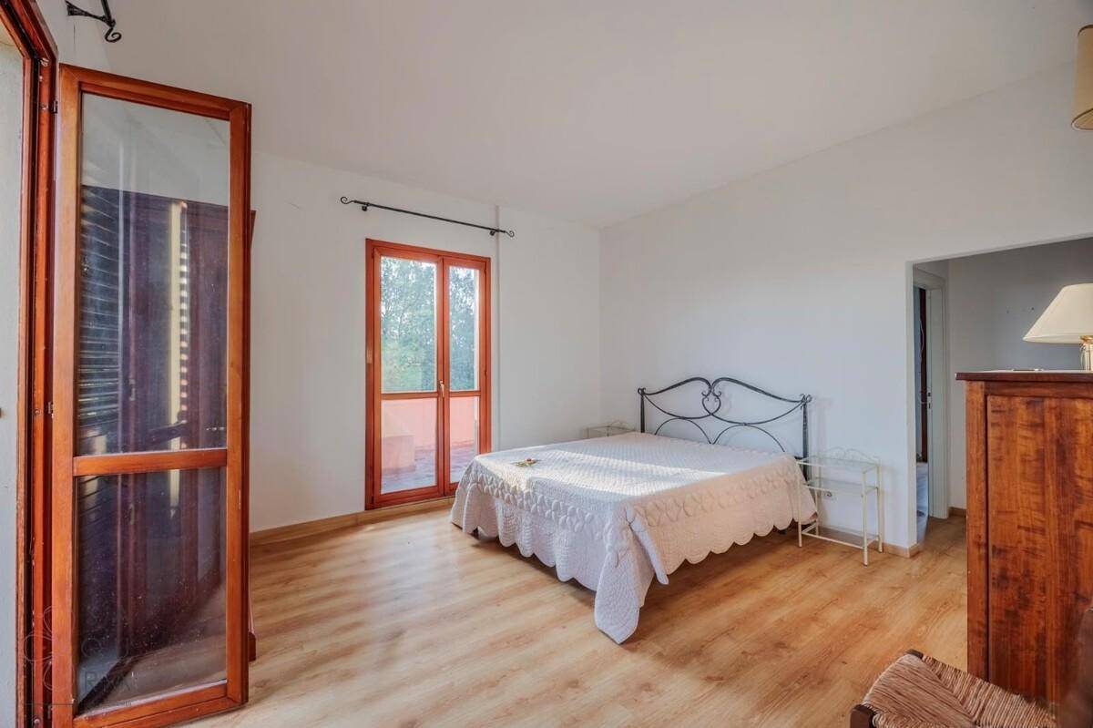 Schlafzimmer mit Doppelbett, Laminatboden und Zugang zu einem Außenbereich.