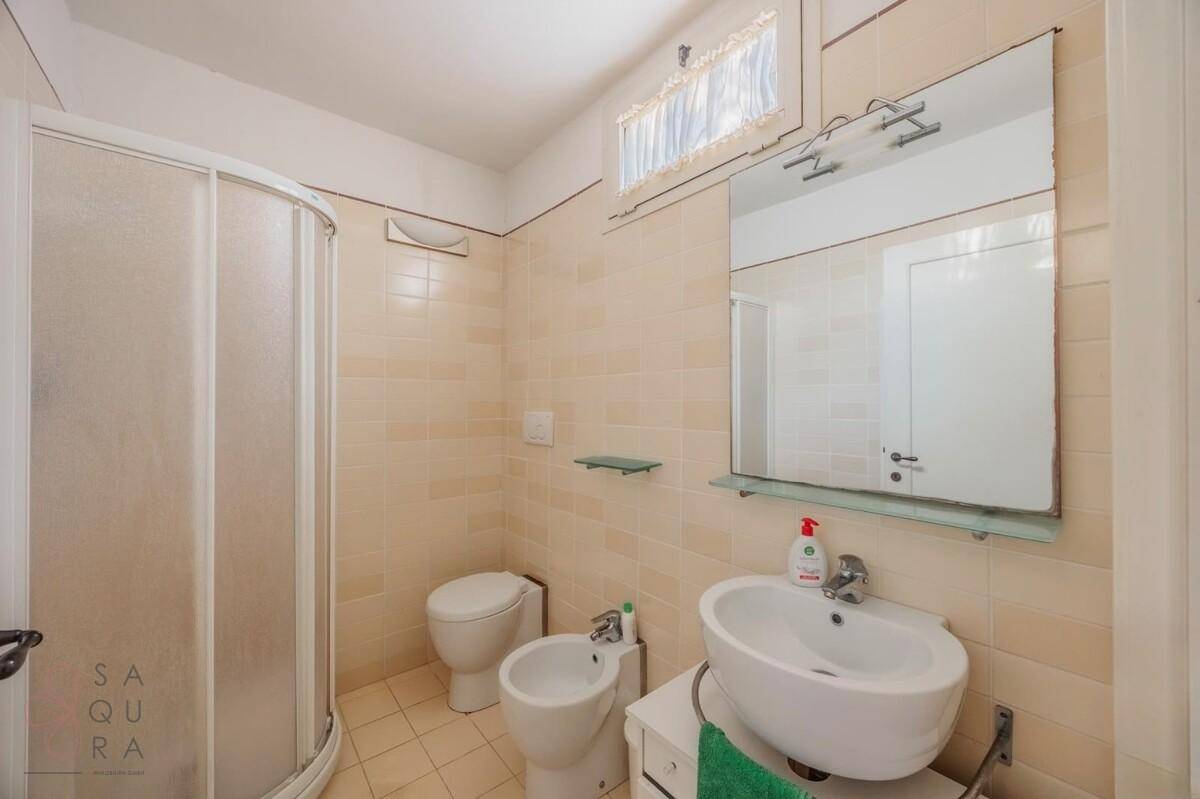 Badezimmer mit Waschbecken, WC, Bidet und einer Eckduschkabine.