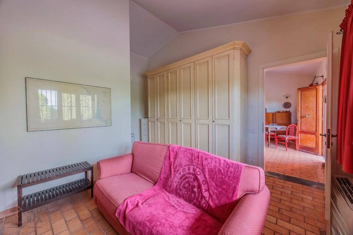 Wohnzimmer mit rosa Sofa, Einbauschränken und traditionellem Terracotta-Fliesenboden.