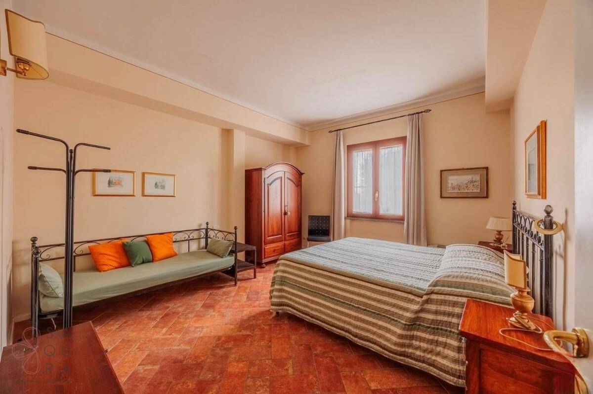 Geräumiges Schlafzimmer mit Doppelbett, Tagesbett, Holzschrank und Terracotta-Fliesenboden.