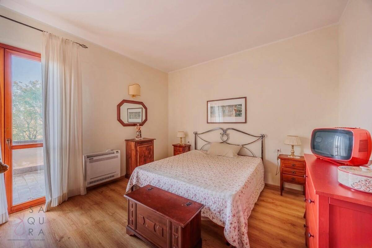 Schlafzimmer mit Doppelbett, Laminatboden und direktem Zugang zu einem Balkon.