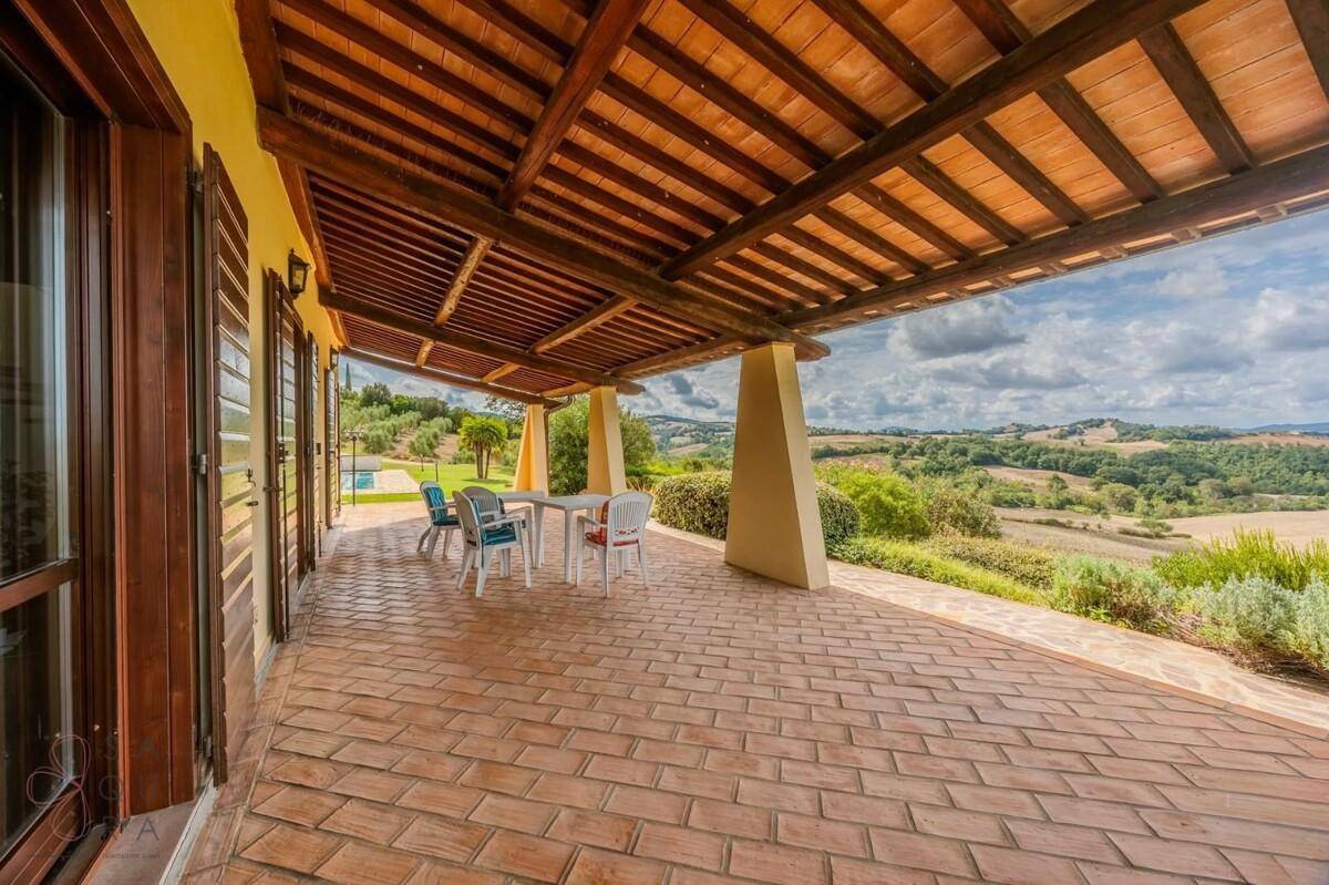Überdachte Terrasse mit Terrakottaboden, Esstisch und weitem Blick über die Landschaft.