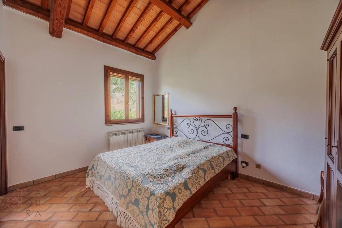 Schlafzimmer im Landhausstil mit Terrakottaboden, Holzbalkendecke und Fenster mit Ausblick.