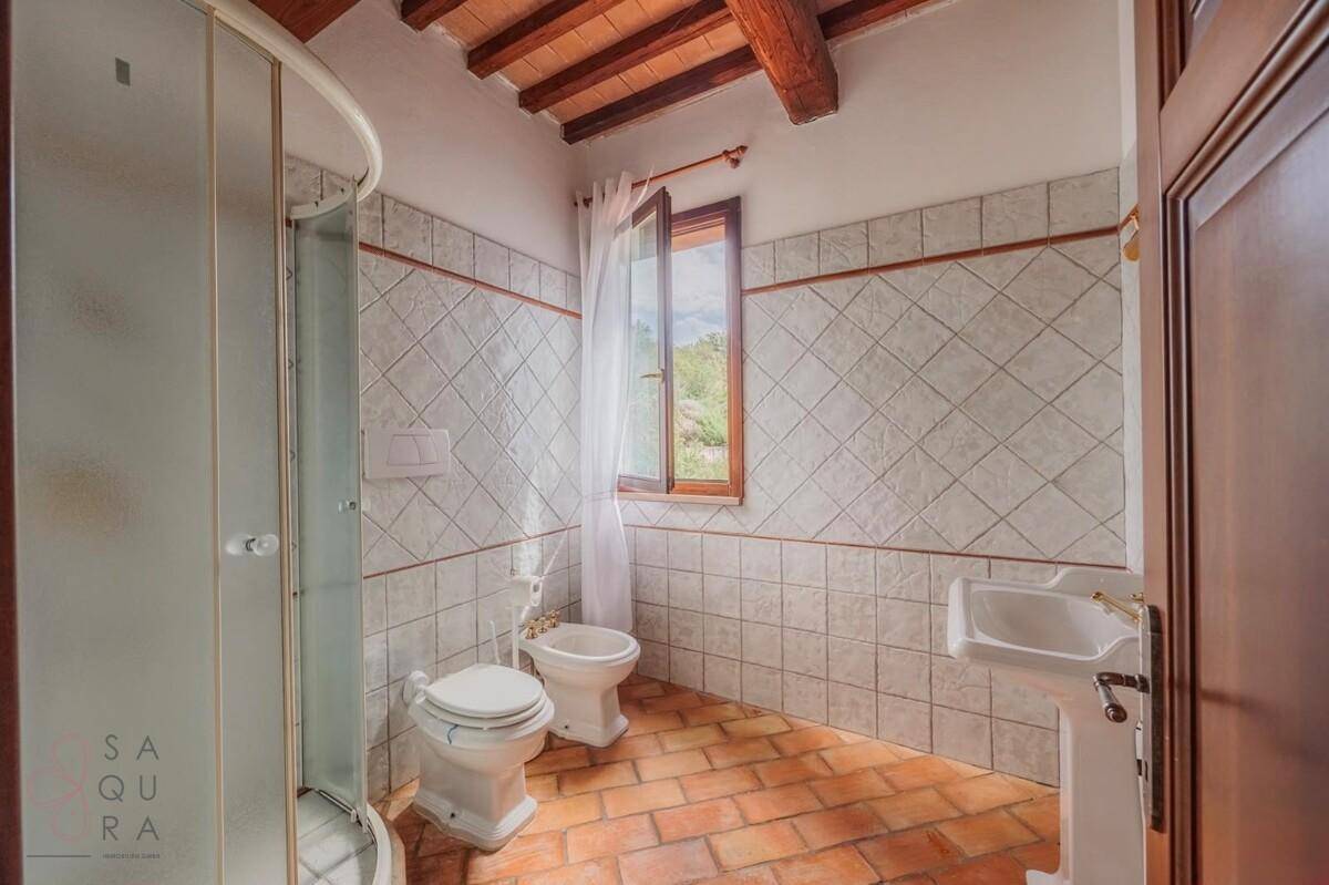 Badezimmer mit Duschkabine, WC, Bidet, Waschbecken und Terrakottaboden.