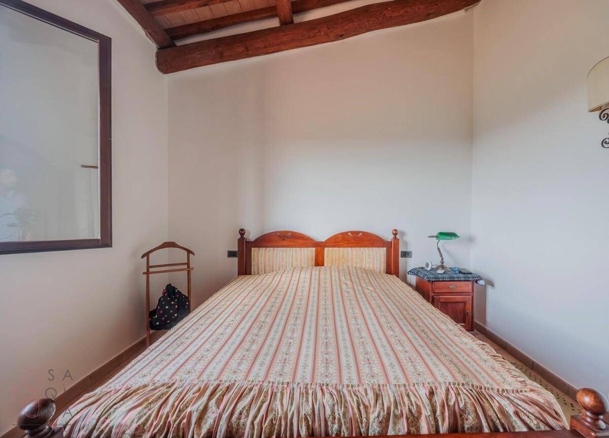 Gemütliches Schlafzimmer mit Terrakottaboden, Holzbalkendecke und traditionellem Bett.