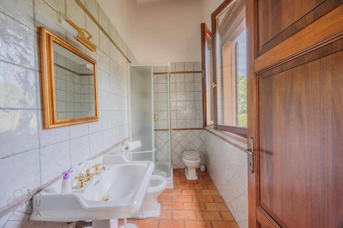 Helles Badezimmer mit Duschkabine, Waschbecken, WC und Fenster.