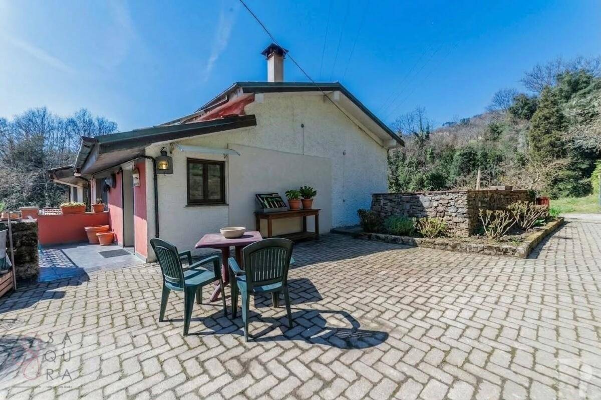 Gepflasterte Terrasse mit Sitzgelegenheiten und einem kleinen Tisch vor einem traditionellen Gebäude.