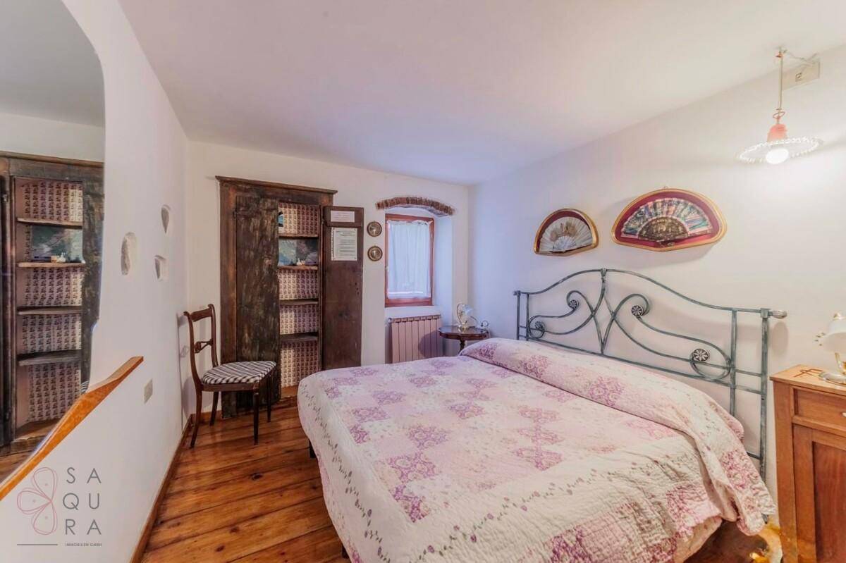 Schlafzimmer mit Doppelbett, Holzboden und einem rustikalen Kleiderschrank, mit traditioneller Dekoration.
