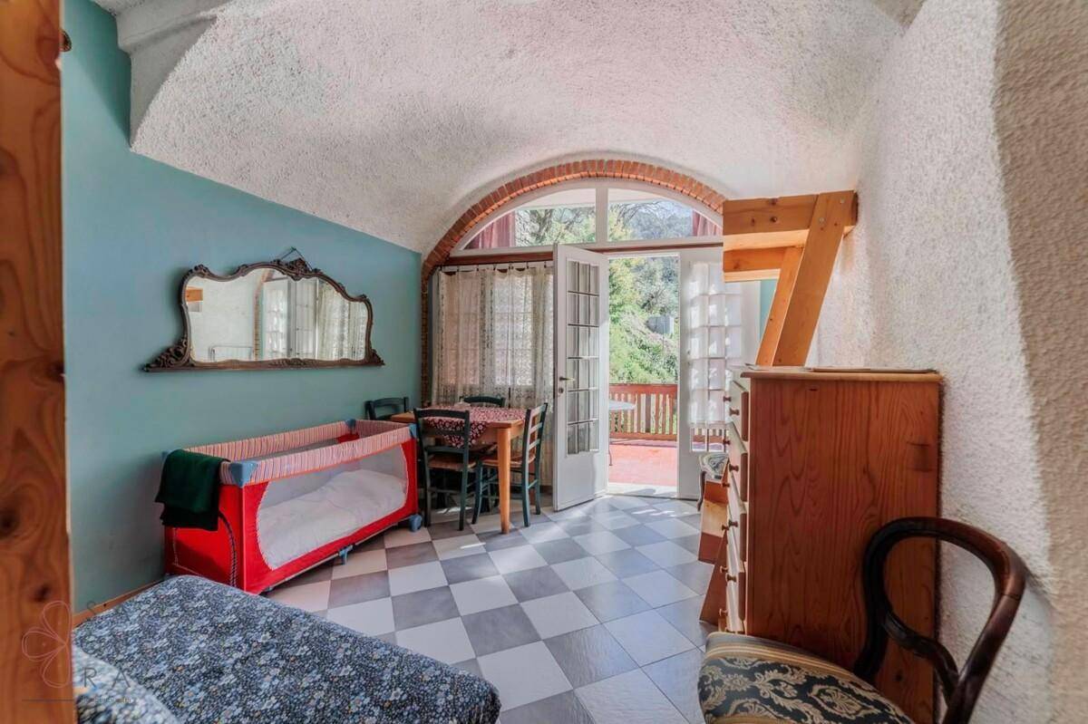 Zimmer mit gewölbter Decke, kariertem Boden, Esstisch und Zugang zu einer Terrasse.