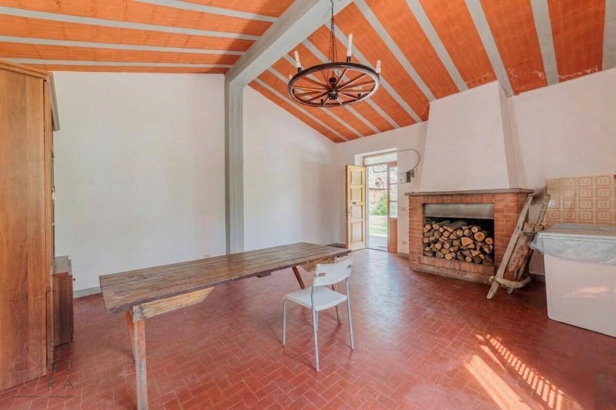 Großer Raum mit hoher, schräger Decke, Kamin und einem langen Holztisch.