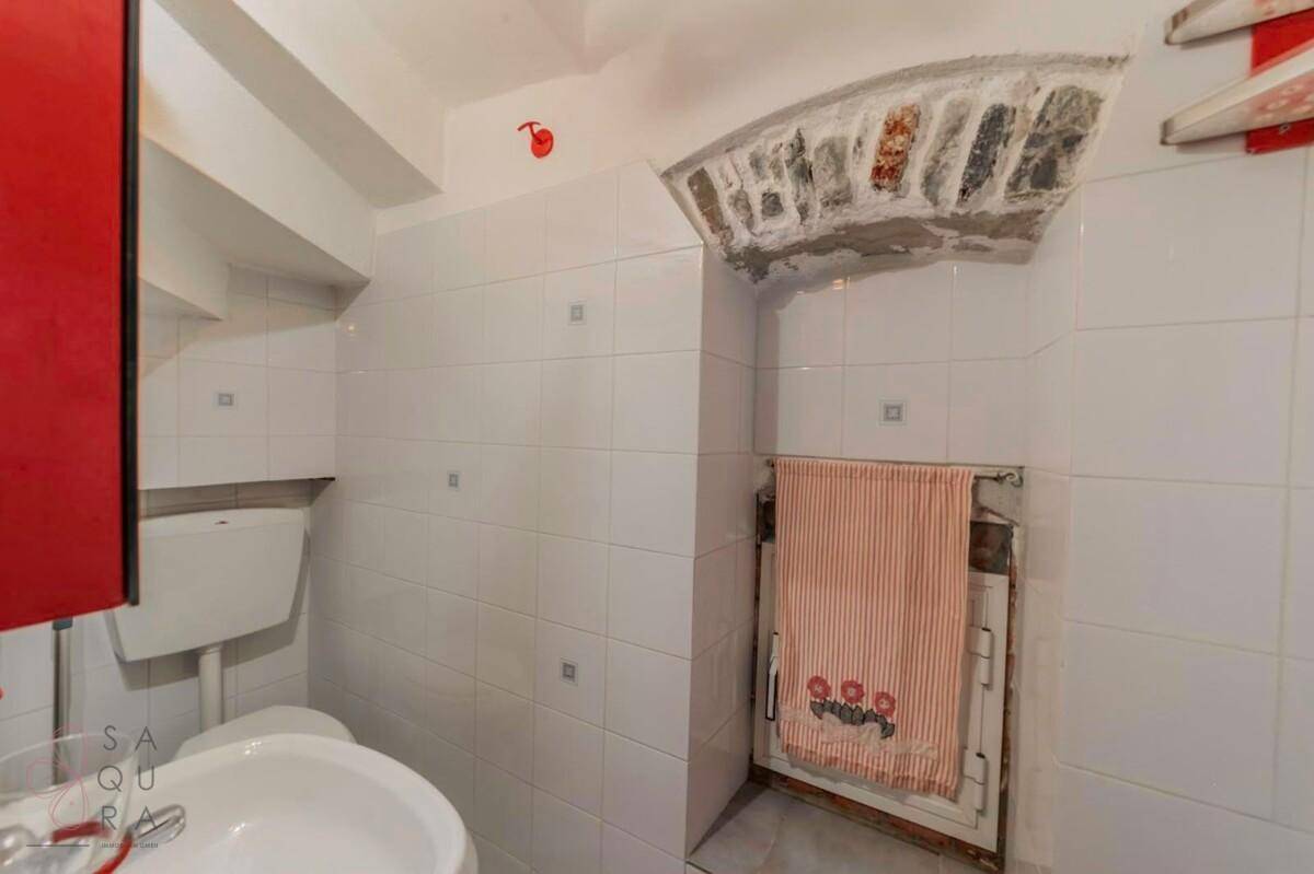 Kleines Badezimmer mit WC, Waschbecken und gefliesten Wänden, mit rustikalen Steinelementen.