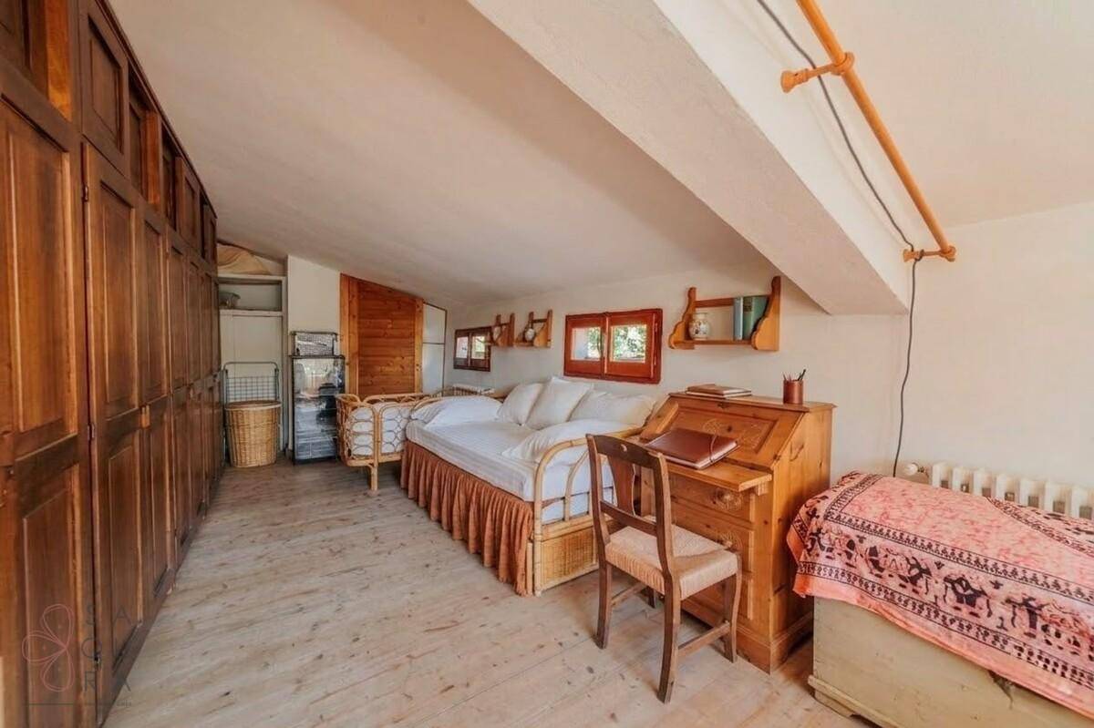 Dachgeschoss-Schlafzimmer mit Holzdielenboden, Einbauschränken und einem Tagesbett, mit Dachschräge.