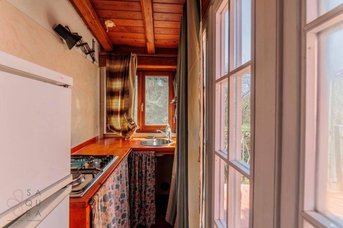 Kleine, schmale Küche mit Gaskochfeld, Spüle, Kühlschrank und einem Fenster.