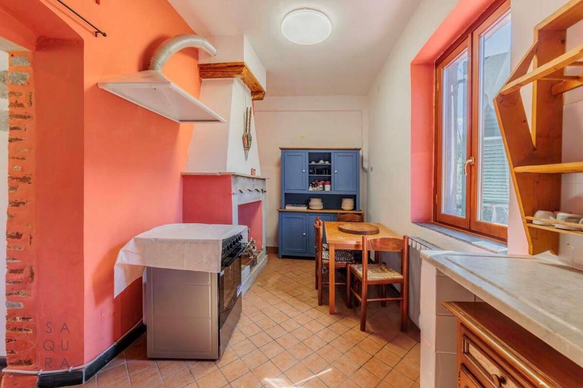 Traditionelle Küche mit orangefarbenen Wänden, Terrakottaboden und einem blauen Buffetschrank.