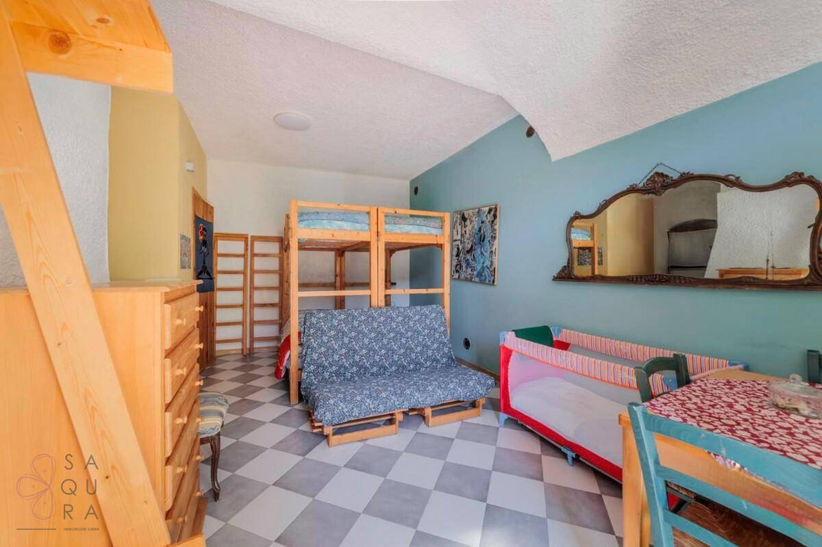 Schlafzimmer mit Etagenbetten, einem Schlafsofa, Babybett und kariertem Fliesenboden.