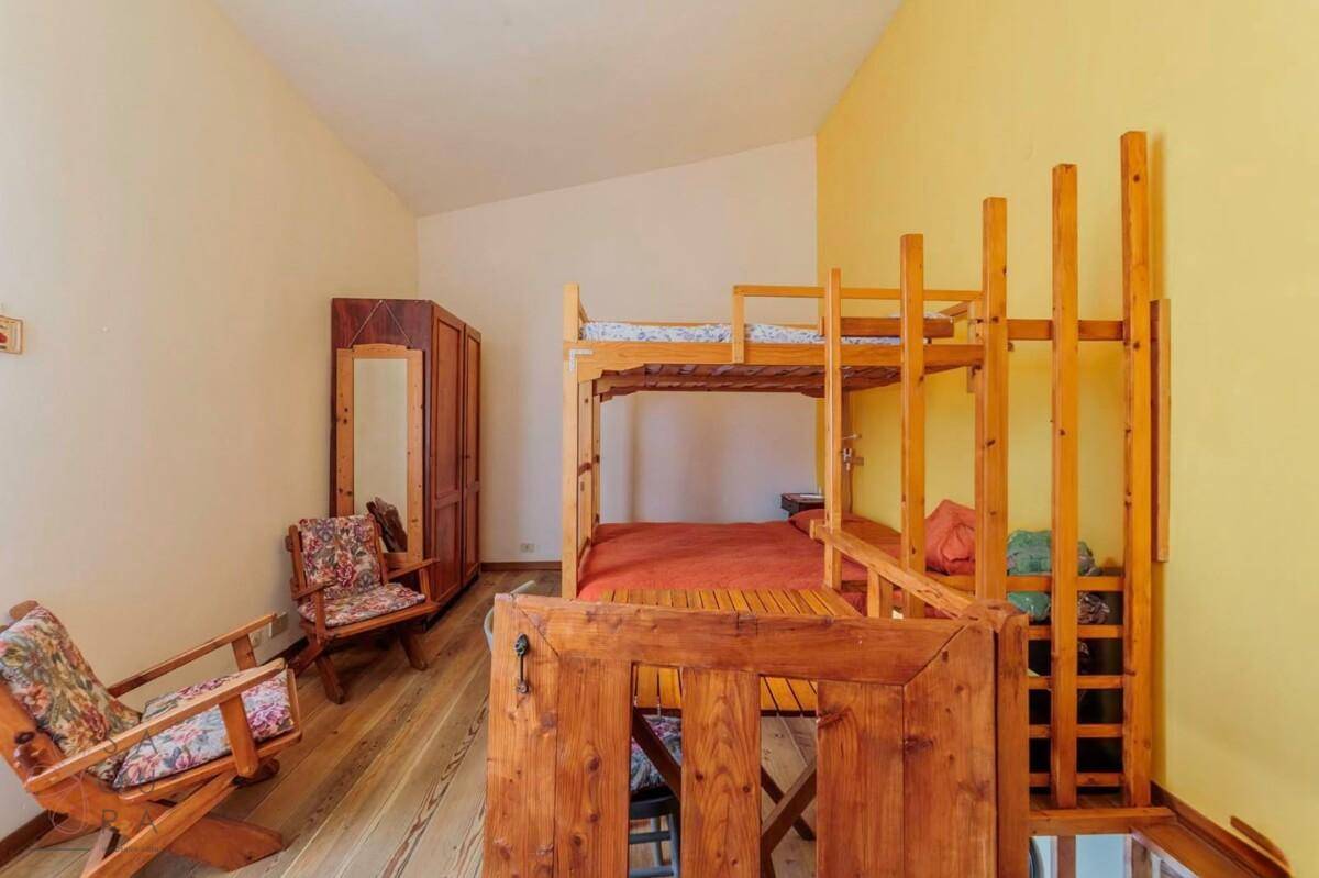 Schlafzimmer mit Holzdielenboden, Etagenbetten, Kleiderschrank und gelb-weißen Wänden.