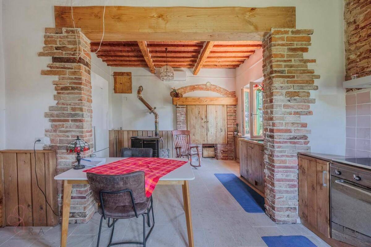 Rustikale Küche mit freiliegenden Ziegelwänden, Holzbalken und einem traditionellen Holzofen.