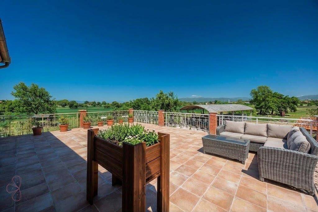 Große geflieste Terrasse mit bequemen Loungemöbeln und weitem Blick in die Landschaft.