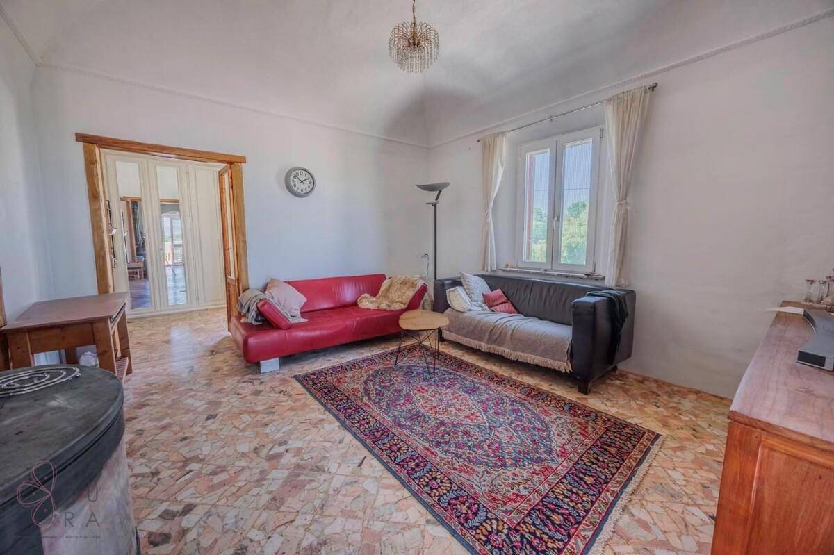 Helles Wohnzimmer mit gemustertem Terrazzoboden, zwei Sofas und einem Kaminofen.