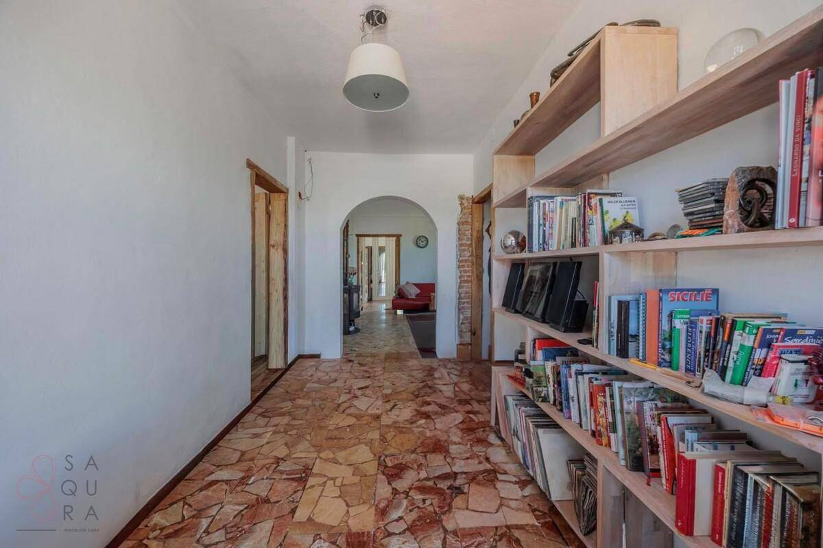 Langer Flur mit Terrazzoboden und eingebauten Bücherregalen, der zu weiteren Räumen führt.