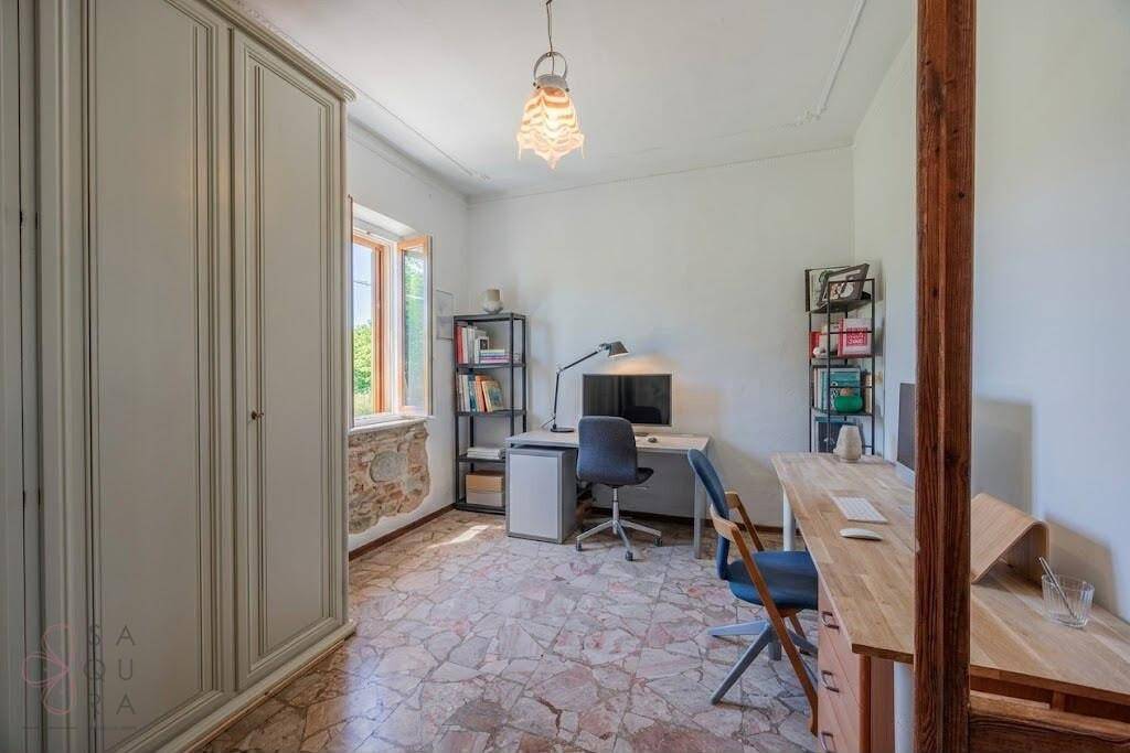 Helles Arbeitszimmer mit zwei Schreibtischen, Bücherregalen und Terrazzoboden.