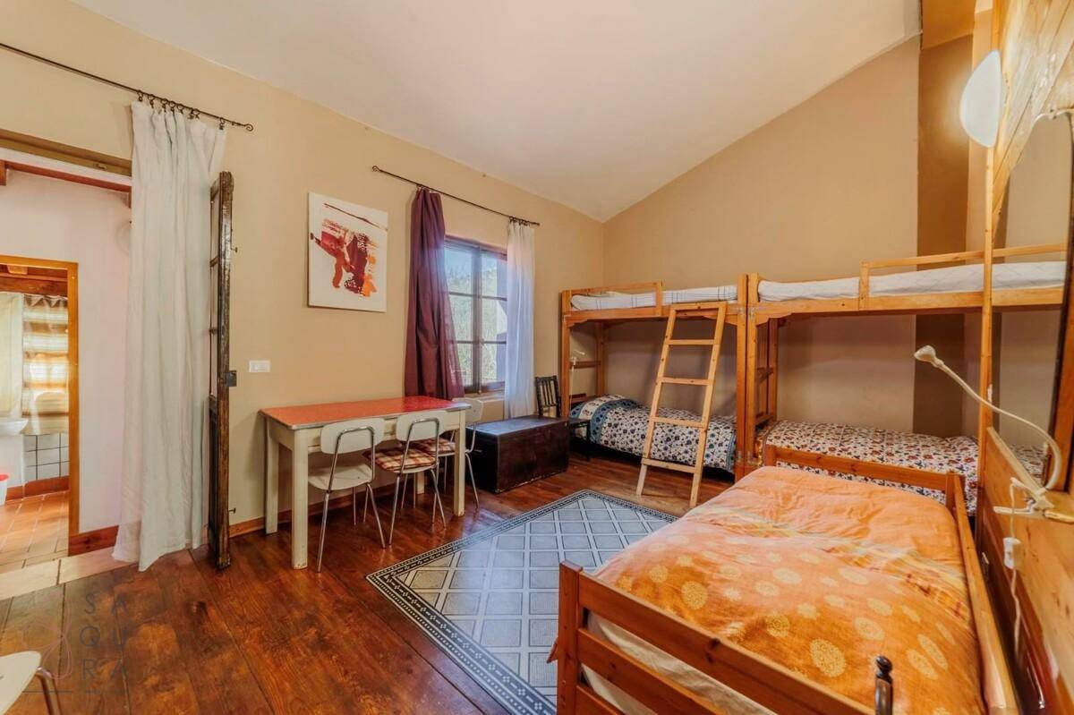 Schlafzimmer mit Holzdielenboden, Etagenbetten, Einzelbett und einem Tisch.