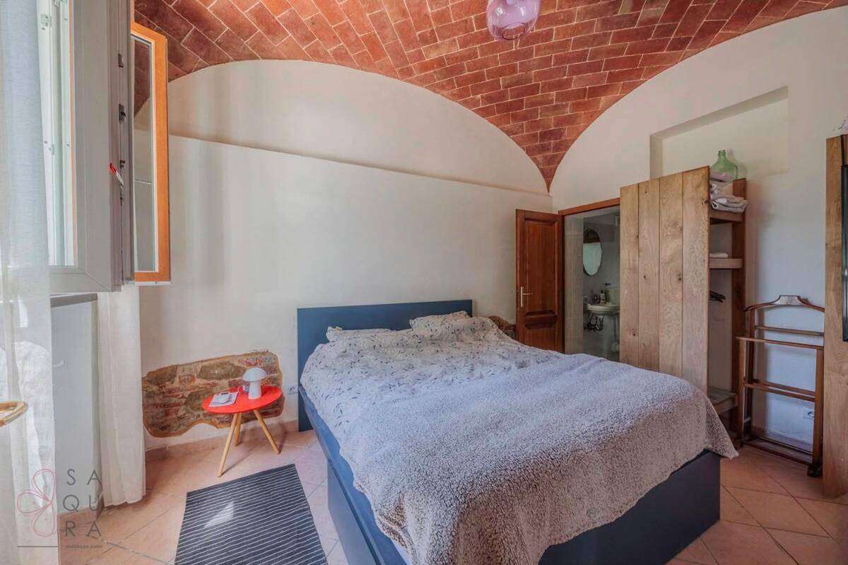 Schlafzimmer mit Gewölbedecke aus Ziegeln und einem Fenster, das viel Licht hereinlässt.