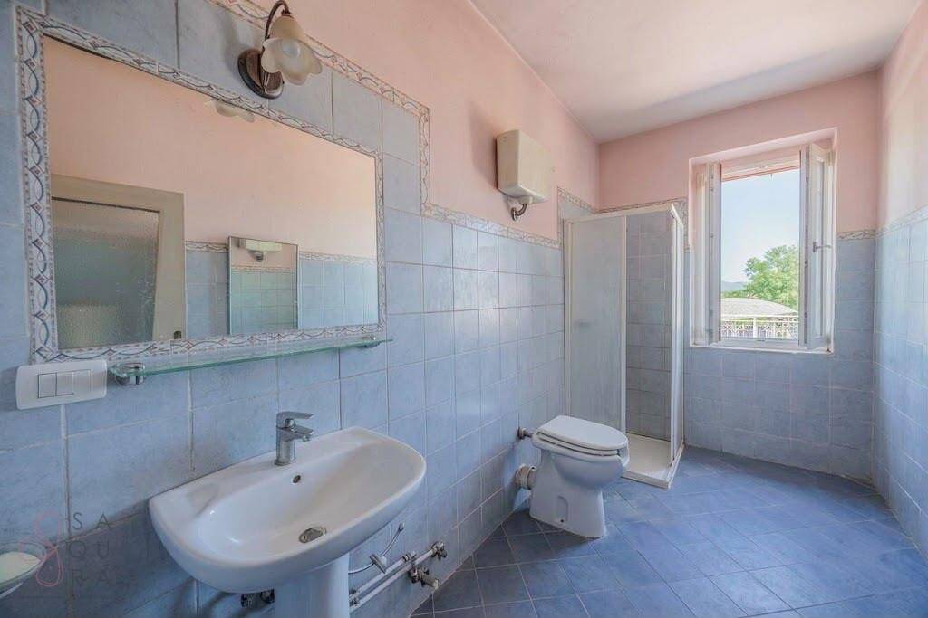 Geräumiges Badezimmer mit blauen Fliesen, Duschkabine und Fenster.
